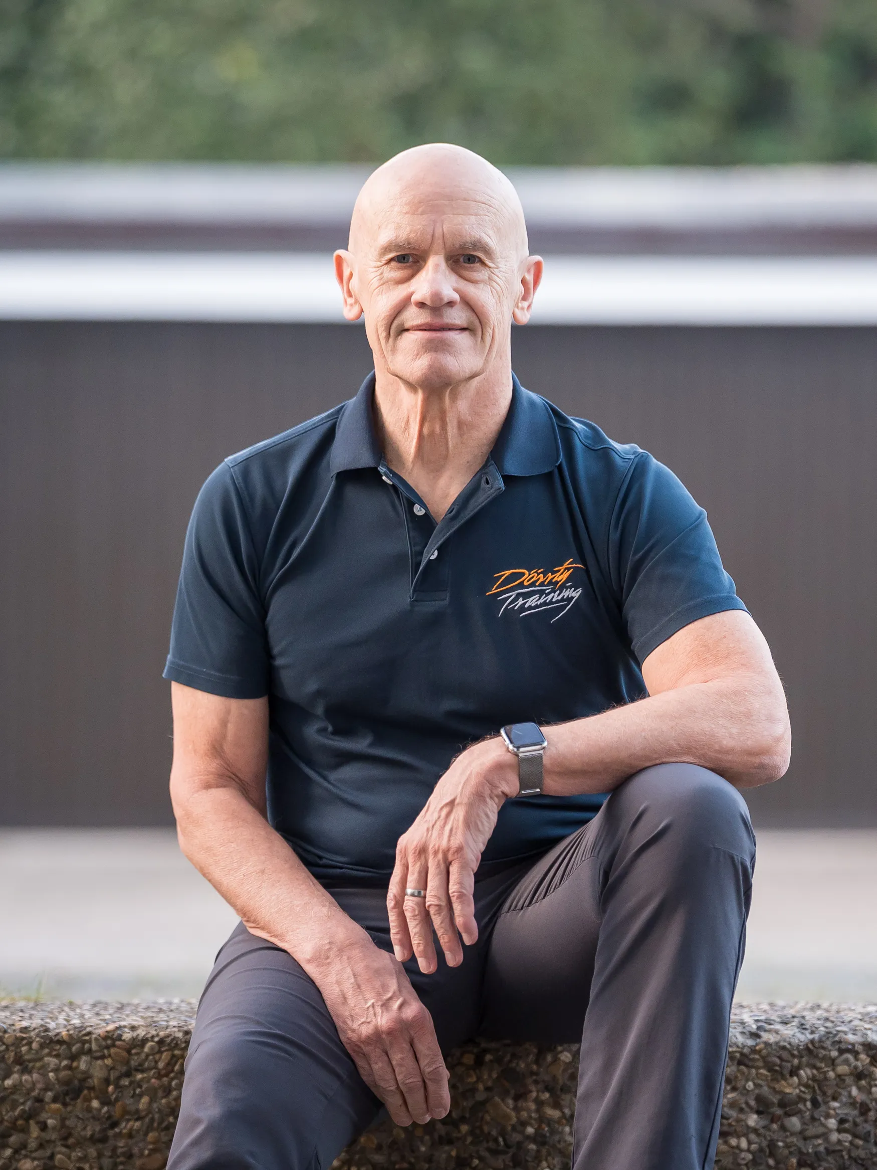 Dr. Michael Dörr sitzt im Dörrty-Training-Poloshirt vor einer Mauer