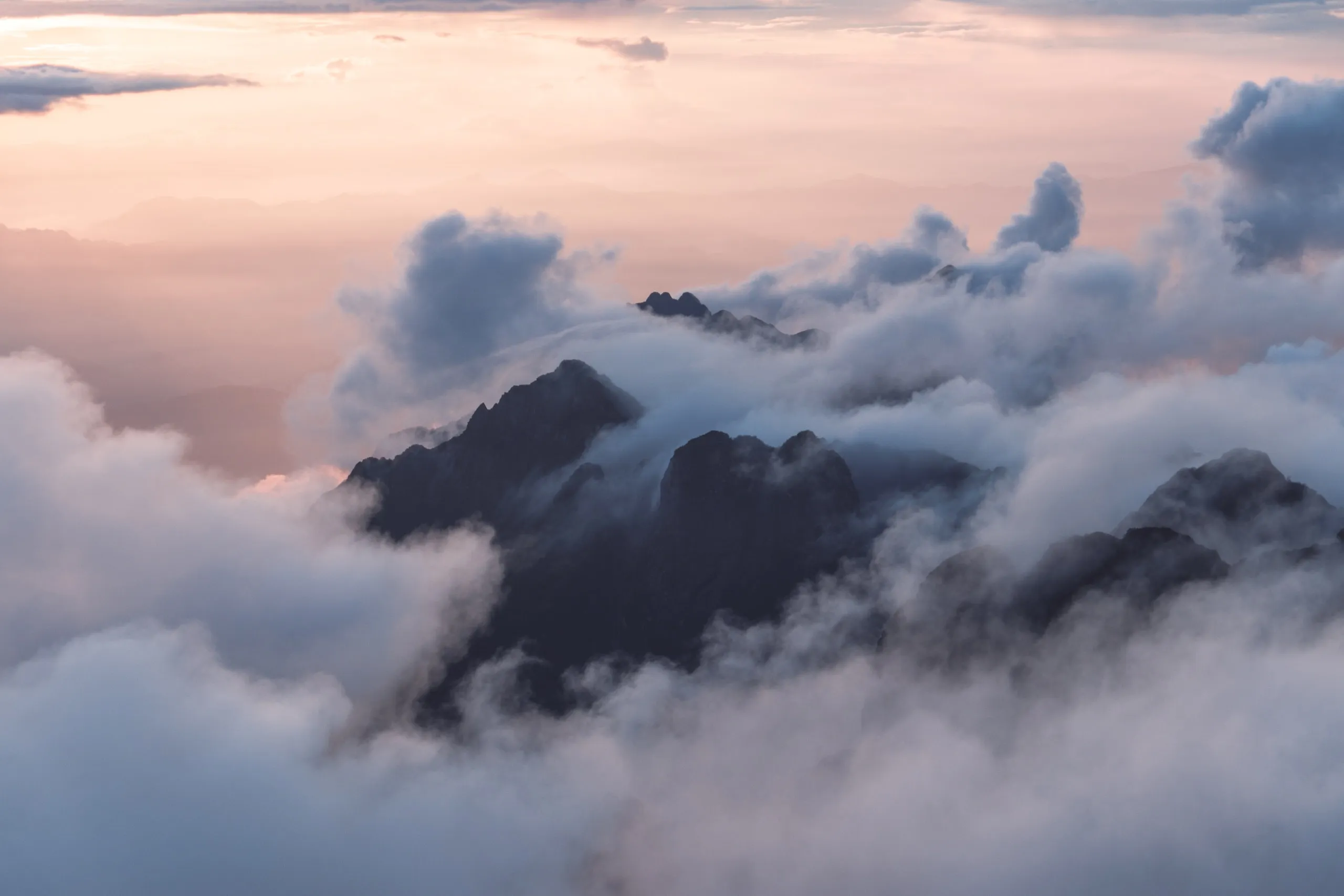 Berggipfel ragen bei Sonnenaufgang aus einem Wolkenmeer