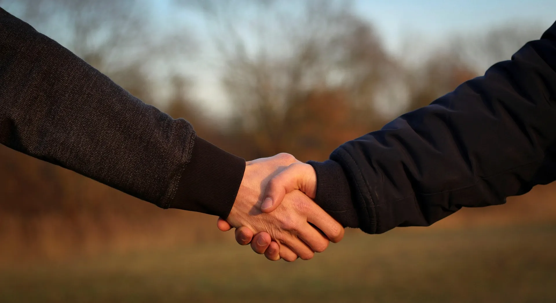 Zwei Personen geben sich im Freien die Hand